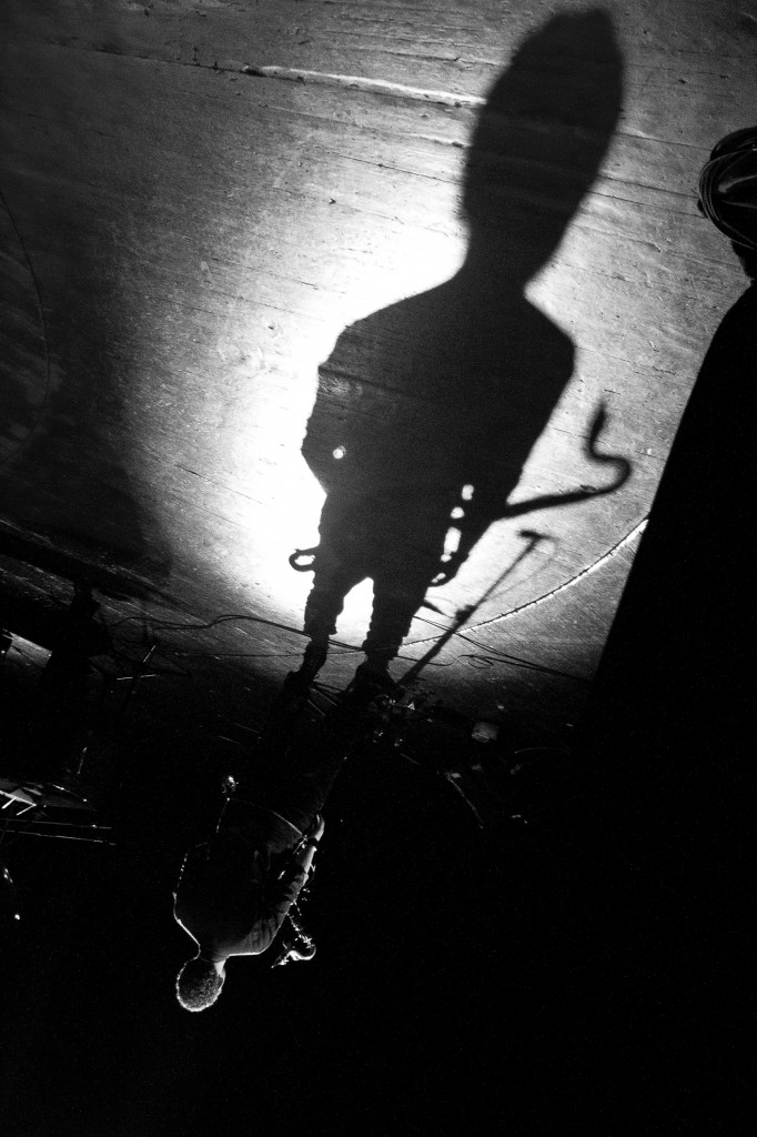Sha playing saxophone beneath a large shadow